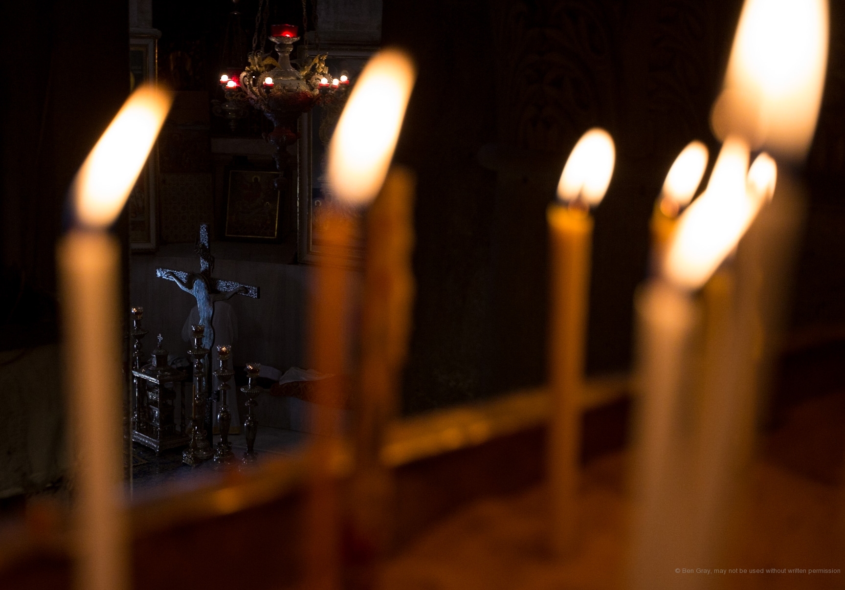 Candles frame a crucifix in the sanctuary of the Greek Orthodox church inside the Church of the Holy Sepulchre.