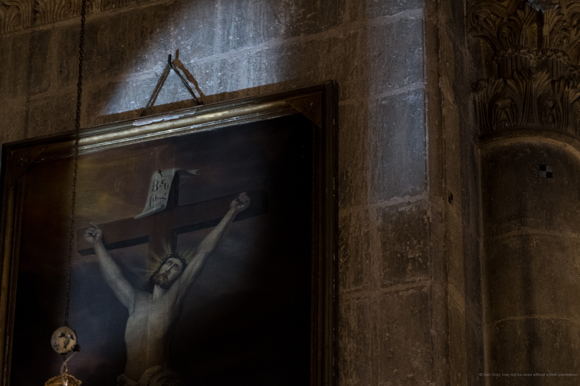 A beam of light hits a painting of the crucified Jesus in the Armenian Chapel of the Division of the Raiment.