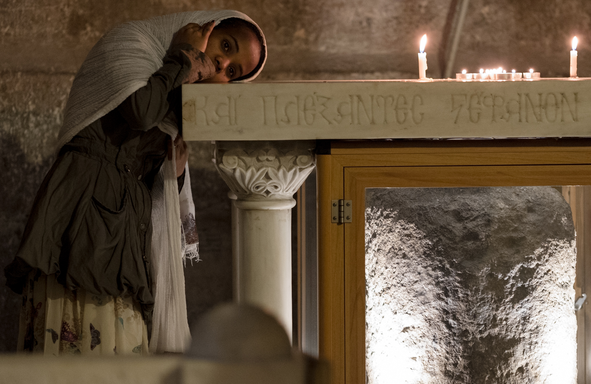 A woman lays her head tenderly upon the alter above a stone where Jesus was believed to have been tied and whipped.