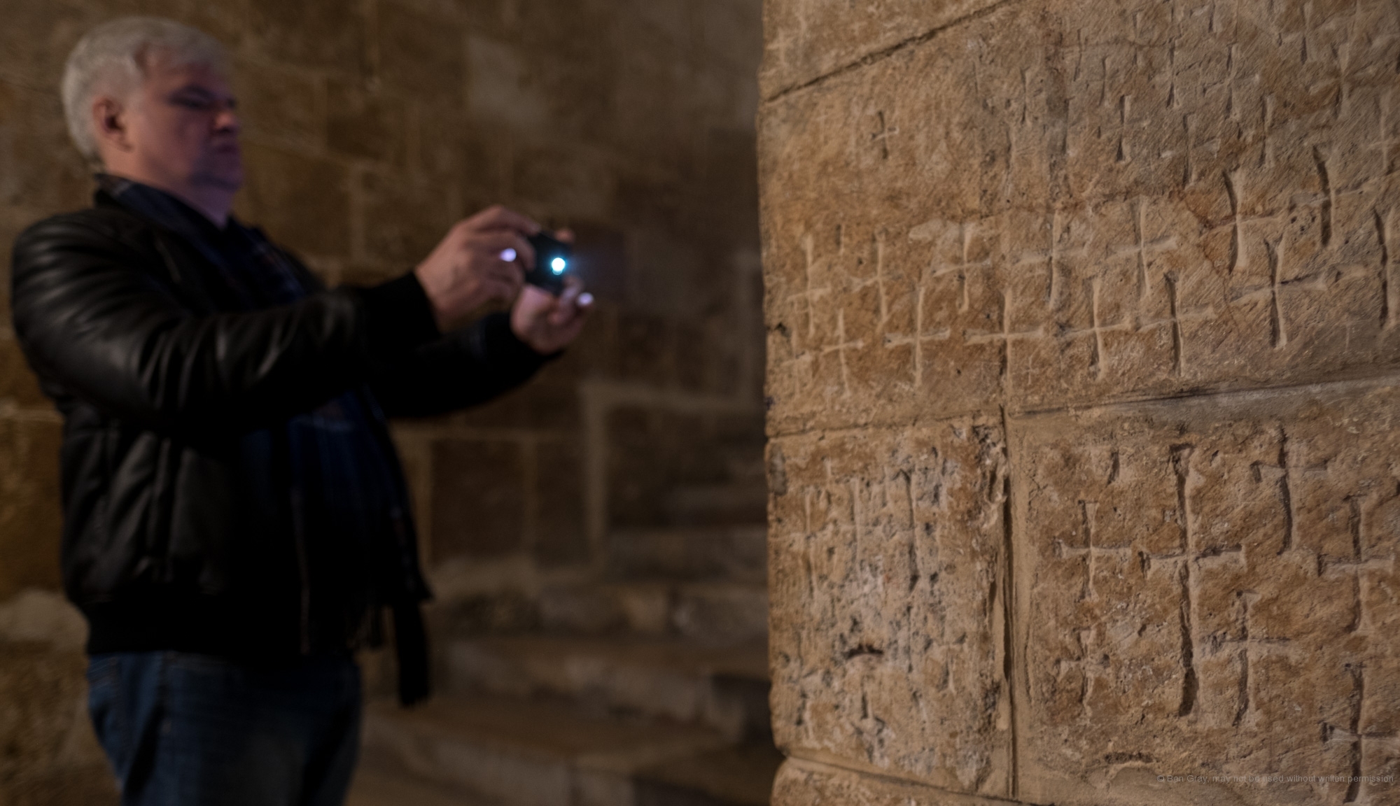 A man takes photos of the Crusader-era crosses carved into the stones of the church.