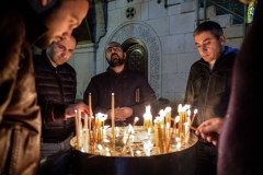 Men light candles and pray near the Holy Tomb.