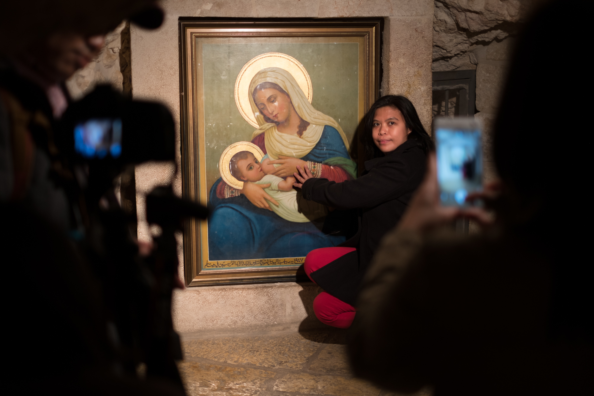A woman poses for photos with the icon of Mary at the Milk Grotto in Bethlehem.