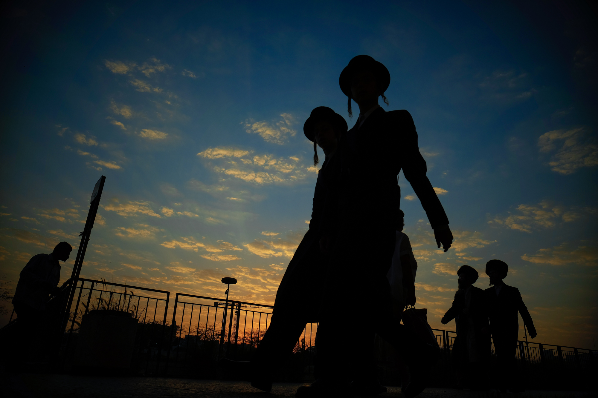 Haredi men head to the Western Wall to pray as the sun sets.
