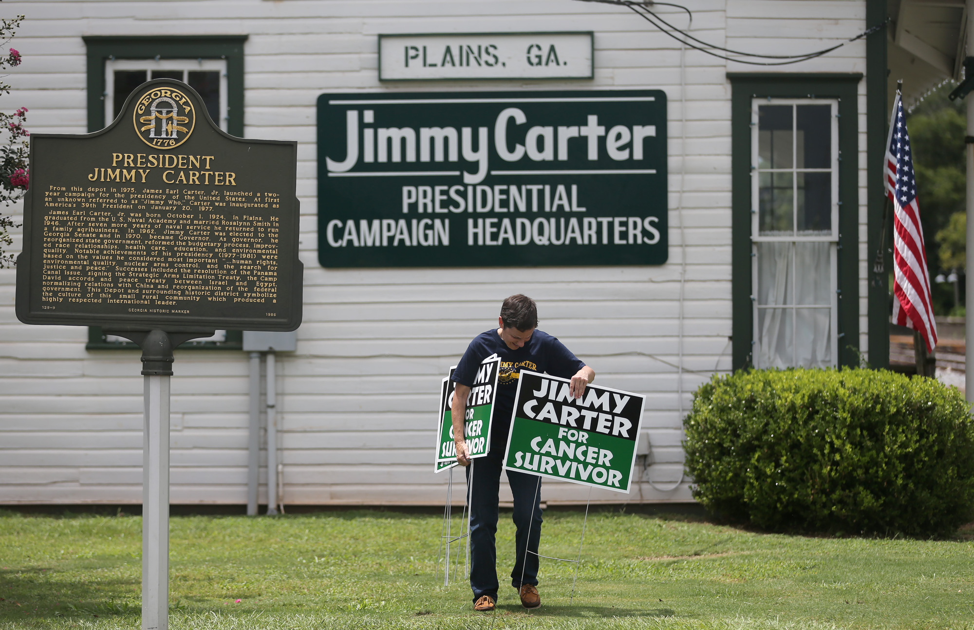 Jill Stuckey places "Jimmy Carter for Cancer Survivor" signs in downtown Plains in advance of the President's return to his hometown. Stuckey printed 500 of the signs after seeing one in a Mike Luckovich cartoon drawn just after Carter announced that he had cancer.