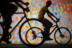 Bicyclists cruise along the Beltline past a mural by HENSE under Virginia Avenue.